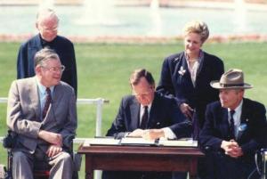 President George H.W. Bush signs into law the Americans with Disabilities Act (ADA) on July 26, 1990.